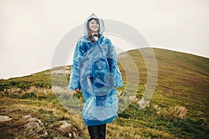 Traveler hipster girl smiling in blue raincoat with backpack, ex