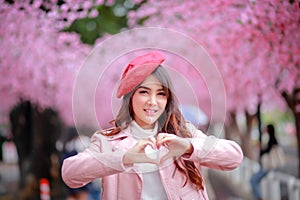 A traveler hipster woman sightseeing wear a red hat and a smooth leather dress with beautiful sakura cherry blossoms tree.
