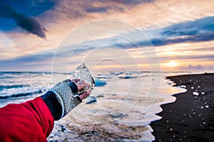 Traveler holding ice chunk on Diamond beach in Iceland