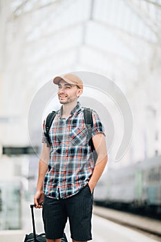 Traveler is late at the train station. Young man with backpack and suitcase missed the train and waiting for next