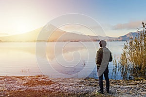 Traveler looking sunrise and mount fuji reflect on water in japan