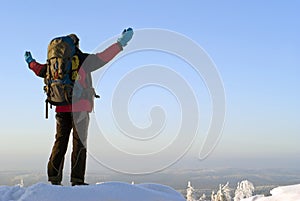 A traveler on top of a winter mountain admires the scenery