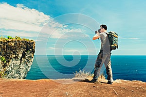 Traveler man backpacker with camera in hand make photo tropical beach on nature background