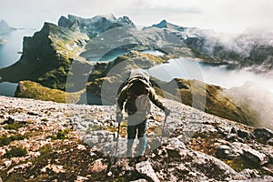 Traveler man climbing to Hermannsdalstinden mountain top in Norway