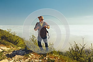 A traveler man climbs to the top of a mountain against a background of clouds on a sunny day. Travel lifestyle