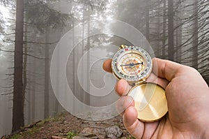 Traveler man with compass seeking a right way in the forest