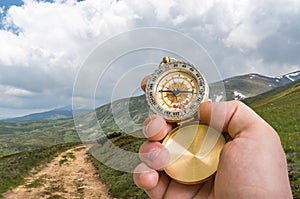 Traveler man with compass seeking a right way in the mountains