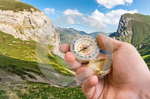 Traveler man with compass seeking a right way in the mountains
