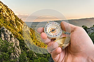 Traveler man with compass seeking a right way in the mountains