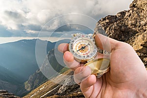 Traveler man with compass seeking a right way in the mountains