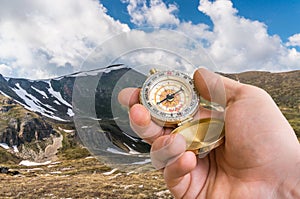 Traveler man with compass seeking a right way in the mountains