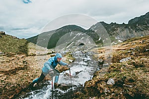 Traveler Man crossing river at mountains survival expedition