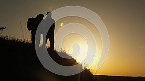 Traveler man extends his hand to a girl climbing to the top of a hill. Travellers climb the cliff holding hand. Teamwork