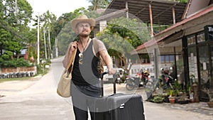 Traveler man in hat with suitcase at luxury resort. tourist on tropical island. travel tourism vacation happy holiday.