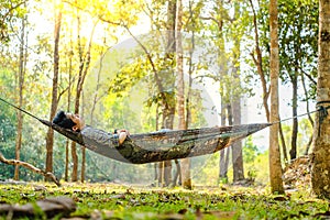 Traveler man hiking and relaxing in hammock autumn woods