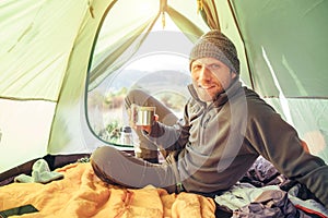 Traveler man meet morning in camping tent with cup of tea