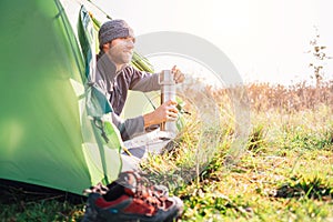 Traveler man meet morning in tent with hot tea