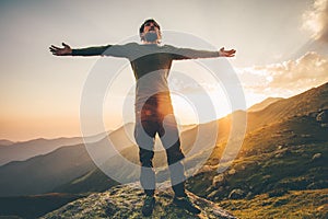 Traveler Man raised hands at sunset mountains