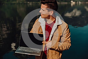 Traveler man relaxing on boat using laptop in amazing nature landscape rock mountain island on lake background