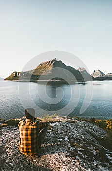 Traveler Man sitting alone admiring sea and mountains view