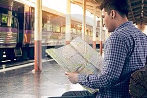 Traveler man sitting at train station and looking on map for travel planning.