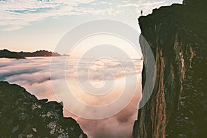 Traveler man standing on the edge cliff over clouds