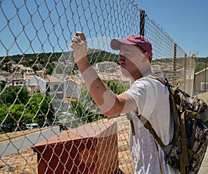 Traveler man stands in a closed area behind a metal bars