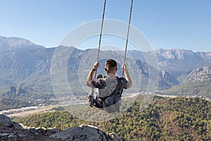 The traveler man on a swing on top of a mountain