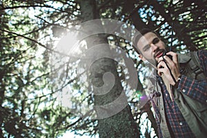 Traveler man talking on radio set in forest