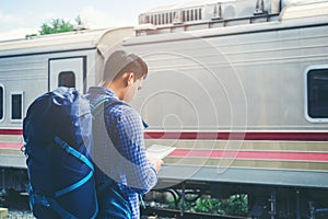 Traveler man using tablet and waits train on railway platform