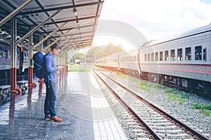 Traveler man waits train on railway platform photo