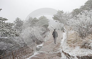 The traveler man walking on the walk way and plenty of the snow cover all of the area on the Huangshan mountain in the winter