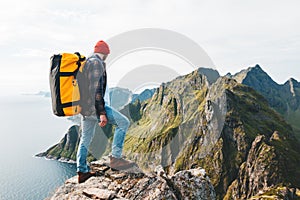 Traveler man wearing backpack and red hat climb on high mountains above sea photo
