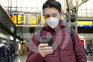 Traveler man wearing KN95 FFP2 protective face mask at the airport. Young caucasian man with behind timetables board of departures