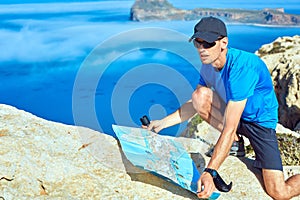 Traveler with map and Spyglass on the cliff