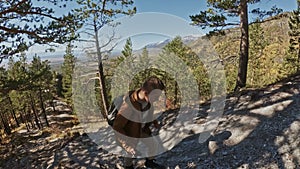 Traveler photographing scenic views in forest by mountain. Man shooting picturesque views. Guy takes photo and video on