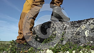 The traveler put his foot on a rock. He`s wearing hiking boots.