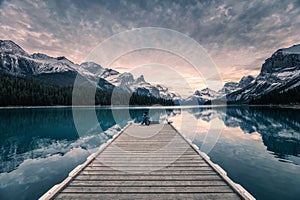 Traveler relaxing on wooden pier in Maligne lake at Spirit island, Jasper national park