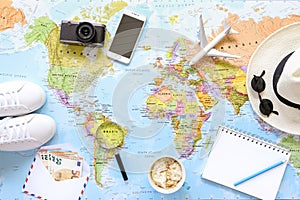 Traveler`s accessories and items with copy space on world map background, travel by airplane concept.