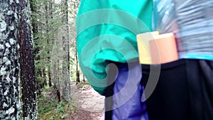 Traveler`s back with backpack in forest. Stock footage. Close-up of traveler goes hiking in woods in cloudy weather