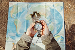 Traveler searching direction with a compass on background of map