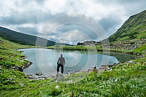 Traveler on the shore of a mountain lake