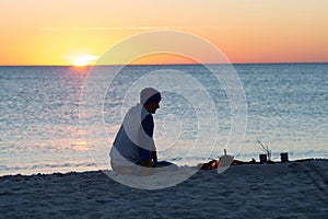 Traveler sits next to a bonfire on the seashore