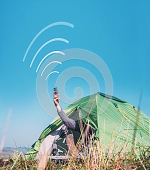 Traveler sits in touristic camping tent and tries to catch cellular network. Cell web coverage and roaming concept image. photo