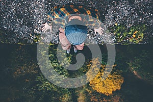 Traveler sitting on cliff bridge edge with forest aerial view