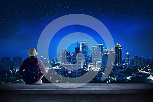 Traveler sitting on the rooftop watching city at night