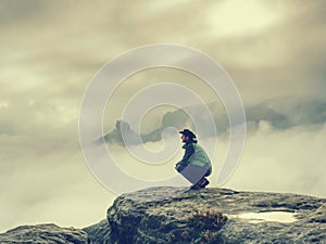 Traveler sitting on the sandstone cliff. Rear view of male hiker