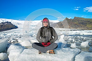 Traveler sitting on small ice shelf and doing meditation