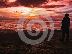 Traveler stand on Rocky cilff with sunsire sky and beautiful cloud sea on `Pa na rai ` Khao Luang mountian