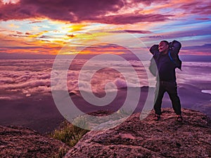 Traveler stand on Rocky cilff with sunsire sky and beautiful cloud sea on `Pa na rai` Khao Luang mountian